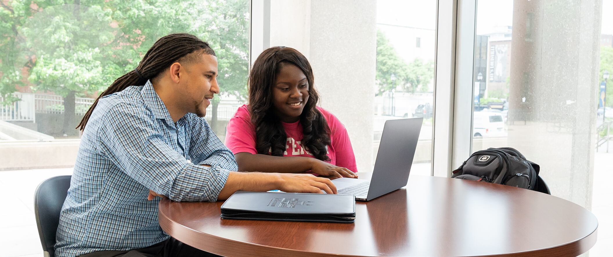 students at lounge table working on laptop