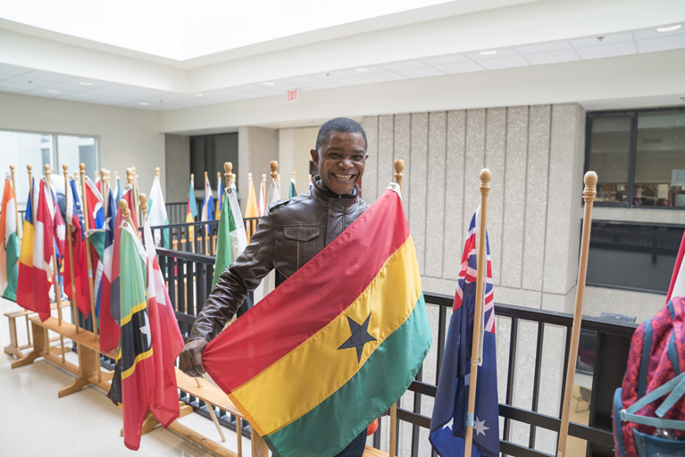 male holding a flag in a room full of different flags