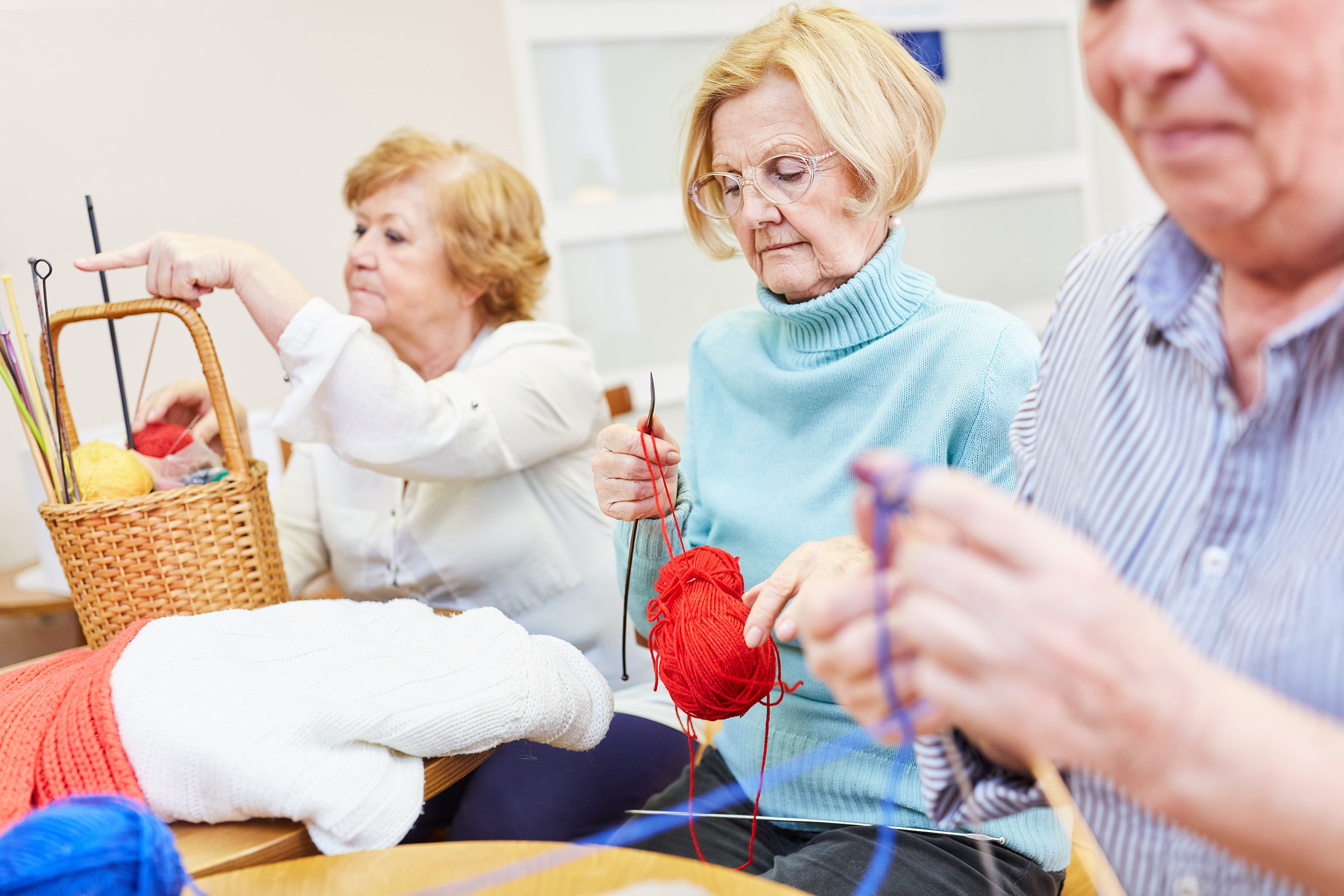 three elderly people knitting