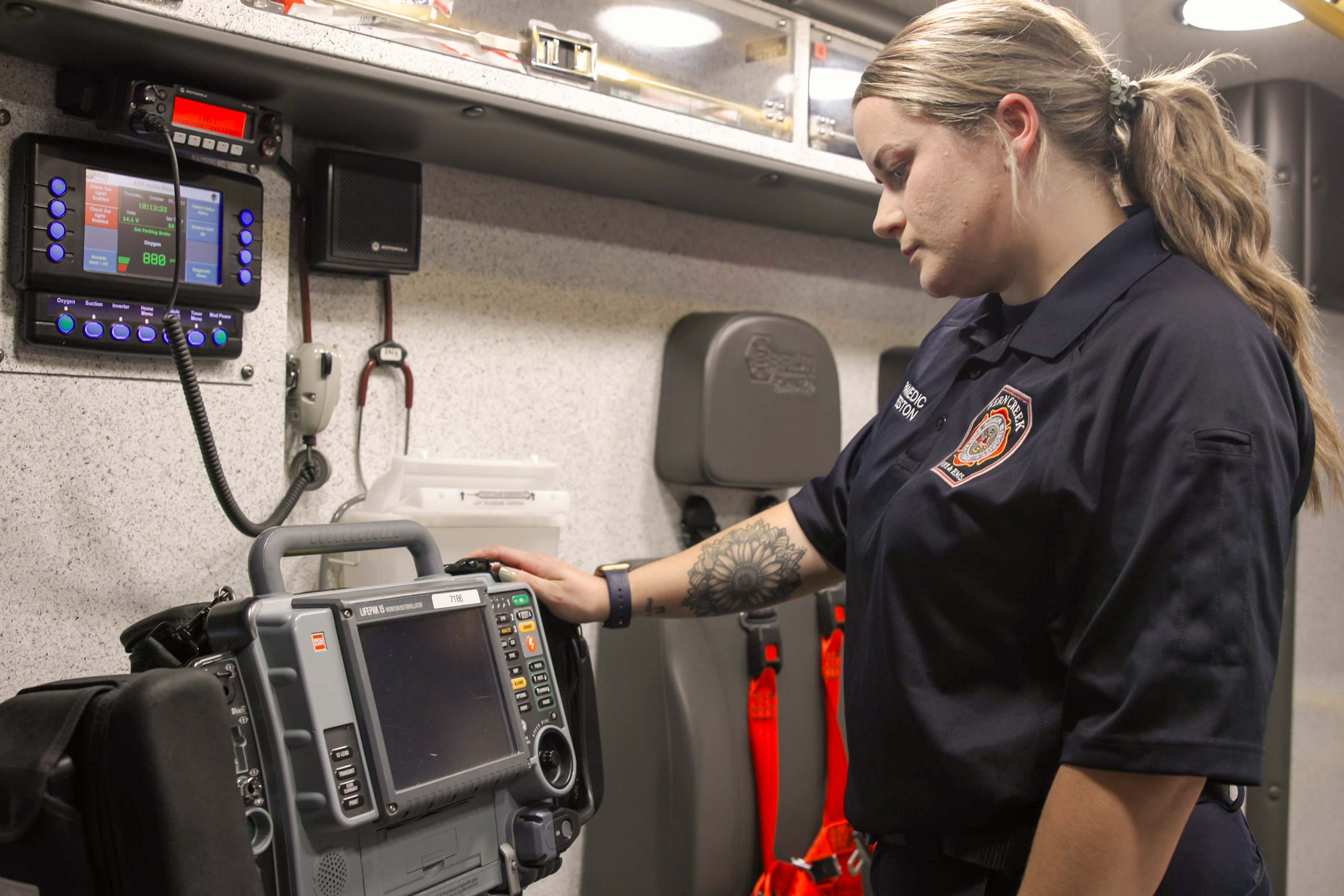 female paramedic looking at a machine in the back of an ambulance